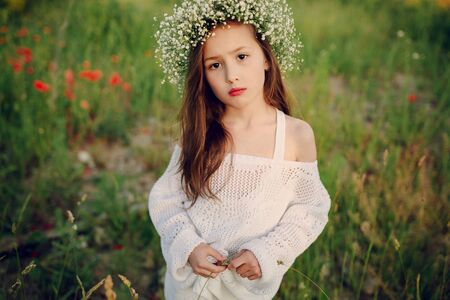 beautiful little girl in a wreath of poppiesの写真素材