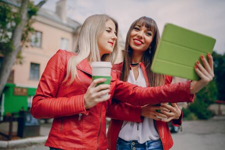 two beautiful girls photographed with gadgets and walk cityの写真素材