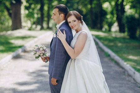 beautiful wedding couple on their wedding walking in the park in excellent weather conditionsの写真素材
