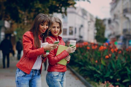 two beautiful girls photographed with gadgets and walk cityの写真素材