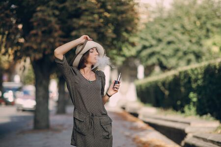 beautiful brunette smoke electronic cigarette in public placesの写真素材