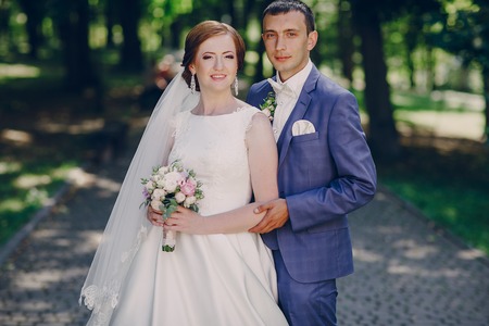 beautiful wedding couple on their wedding walking in the park in excellent weather conditionsの写真素材