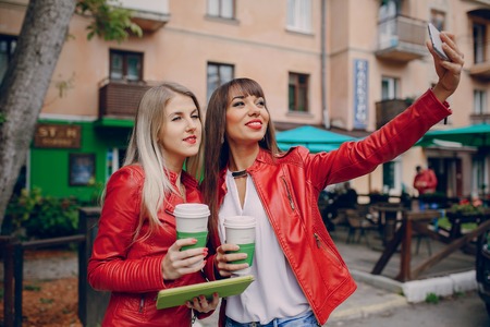 two beautiful girls photographed with gadgets and walk cityの写真素材