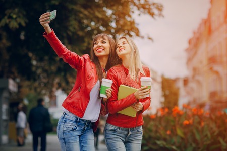 two beautiful girls photographed with gadgets and walk cityの写真素材