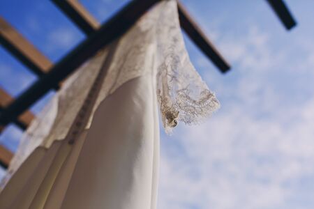 gorgeous wedding dress hanging outside on a sunny dayの写真素材