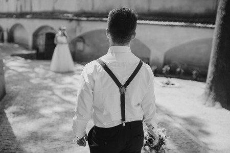 charming wedding couple in wreaths and suspendersの写真素材