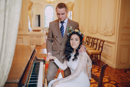 charming wedding couple playing on an old piano in the roomの写真素材