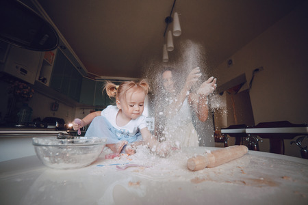 young beautiful mother teaches daughter prepare dough in the kitchenの写真素材