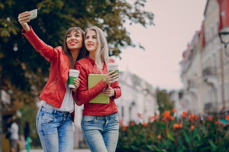 two beautiful girls photographed with gadgets and walk cityの写真素材