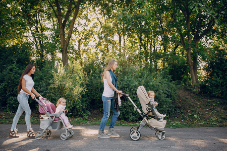 young mother walking with her baby and carries it in a beautiful pramの写真素材