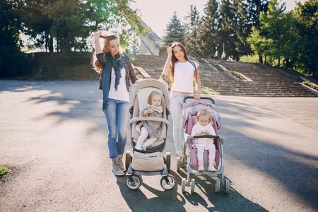 young mother walking with her baby and carries it in a beautiful pramの写真素材