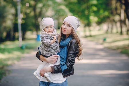 great trendy young mothers walking in the park with his daughters in beautiful clothingの写真素材