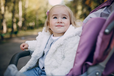 little  and very beautiful girl sitting in the pram and waiting for mom