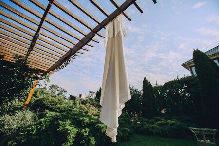 gorgeous wedding dress hanging outside on a sunny dayの写真素材