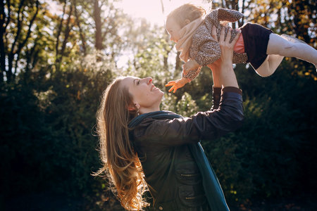 great trendy young mothers walking in the park with his daughters in beautiful clothing