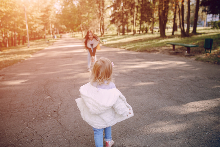 great trendy young mothers walking in the park with his daughters in beautiful clothingの写真素材