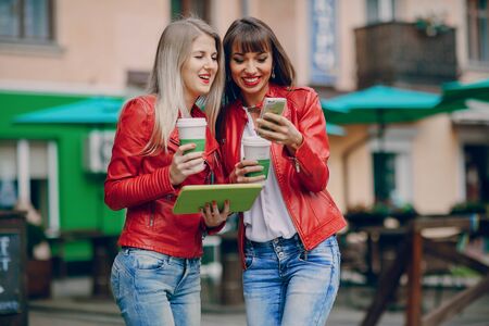 two beautiful girls photographed with gadgets and walk cityの写真素材