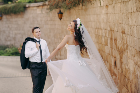 gorgeous wedding couple enjoys a Sunny day in the old town with architectureの写真素材
