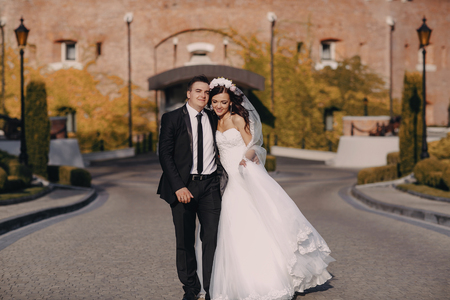 gorgeous wedding couple enjoys a Sunny day in the old town with architectureの写真素材