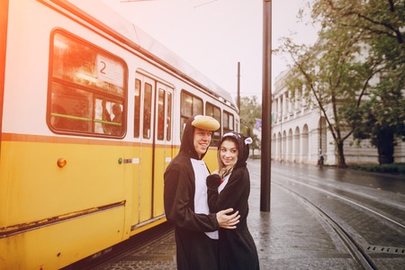 wonderful cheerful couple walking on a rainy Budapest in cat suitsの写真素材