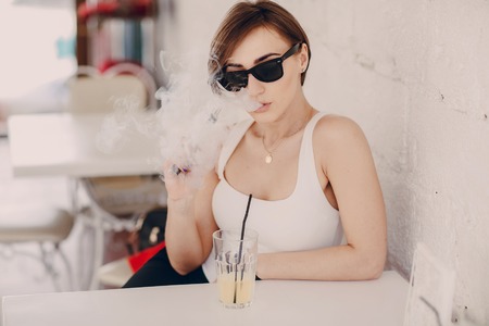 spectacular young brunette enjoys fashion and healthy electronic cigaretteの写真素材