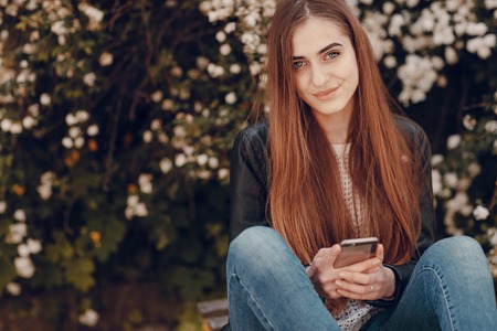 beautiful girl on the street using cell phones, a tablet and walksの写真素材