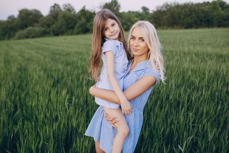 mom and daughter in beautiful dresses walk in field of beautiful summer weatherの写真素材