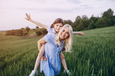 mom and daughter in beautiful dresses walk in field of beautiful summer weatherの写真素材