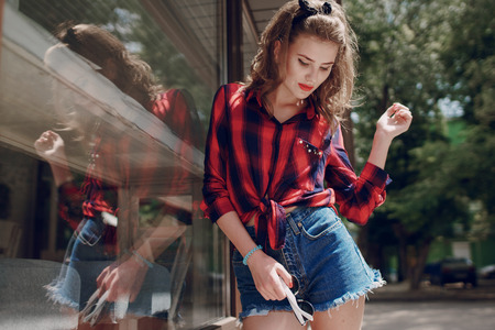 beautiful girl, brightly dressed in the style of pin-up walks in with glassesの写真素材