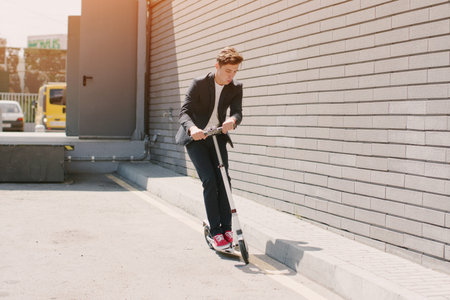 young man on the scooter walks through the city on Sunny day