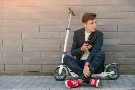 young man on the scooter walks through the city on Sunny day