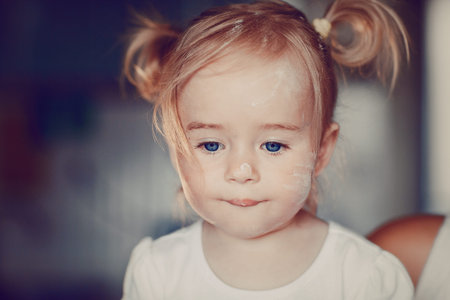 beautiful little girl learns to cook a meal in the kitchenの写真素材