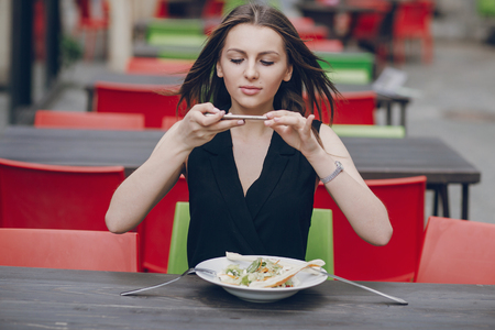 young beautiful brunette enjoys gadgets, photographs, and lunchの写真素材