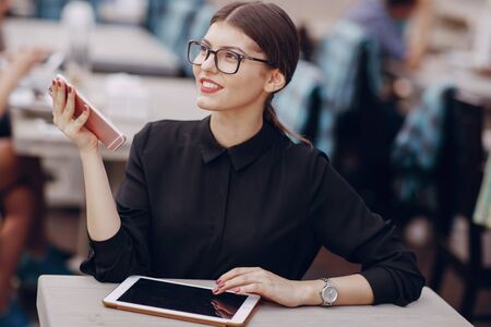beautiful business lady drinking coffee and uses different gadgetsの写真素材