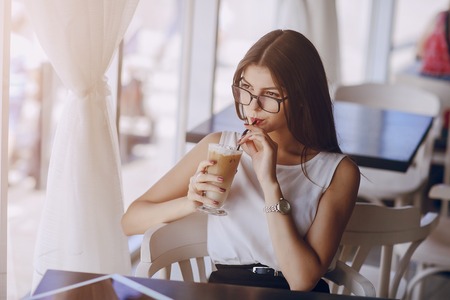 beautiful business lady drinking coffee and uses different gadgetsの写真素材