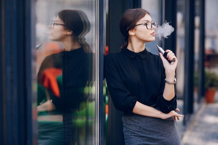 beautiful brunette girl uses an electronic cigaretteの写真素材