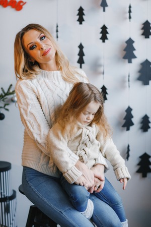 mother and daughter sitting by holiday decorationsの写真素材
