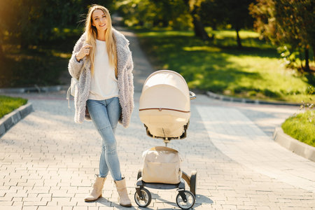 stylish young blonde mother pushing stroller