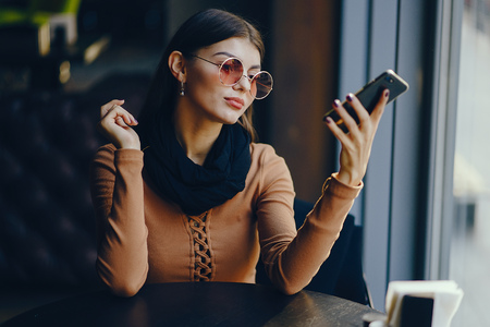 brunette girl using phone while at a restaurantの写真素材
