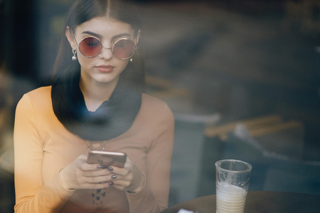 brunette girl using phone while at a restaurantの写真素材
