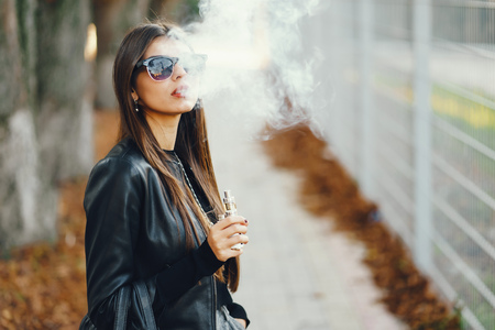 stylish girl smoking an e-cigaretteの写真素材