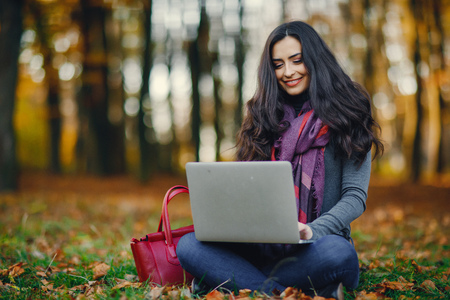 brunette girl working on her laptop in the parkの写真素材