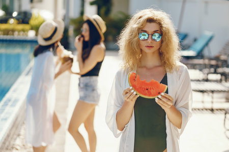 three girls eating fruit at the poolの写真素材