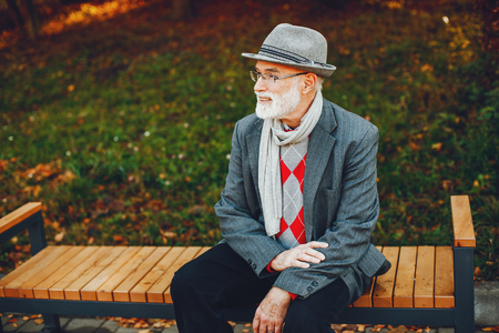 Elegant old man in a sunny autumn parkの写真素材