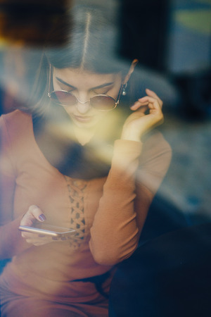 brunette girl using phone while at a restaurantの写真素材