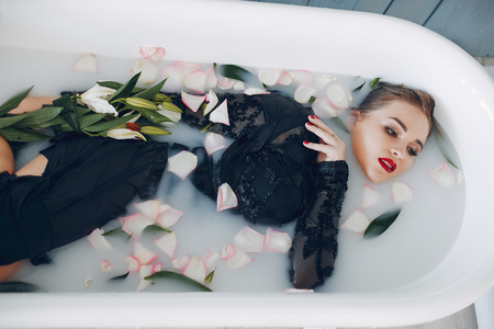 Stylish and beautiful girl lies in the bathroomの写真素材