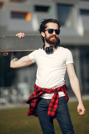 Stylish guy with skate in a summer cityの写真素材