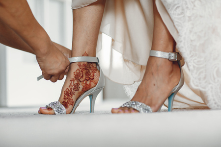Beautiful bride in a white dress. Woman with gold bracelets. Lady with mehendi on her legsの写真素材