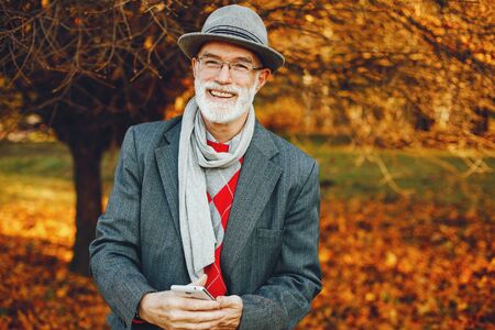 Elegant old man in a sunny autumn parkの写真素材