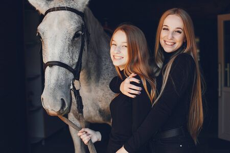 Elegant girls with a horse in a ranchの写真素材